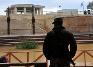 Jordanian soldier looks at rival baptism site across the narrow River Jordan in Israel