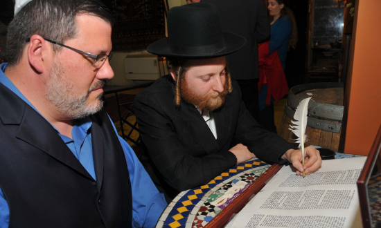 AJPA president Marshall Weiss helps inscribe a letter in the EL AL Torah 